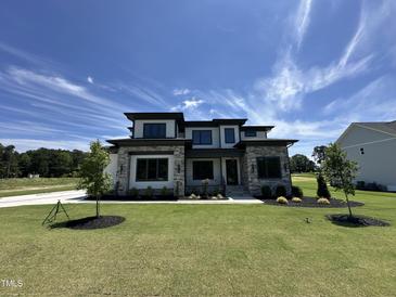 Beautiful two-story home with a well-manicured lawn and stone accents under a clear blue sky at 200 Broadleaf Ln, Youngsville, NC 27596