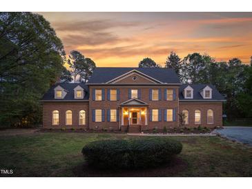 Stately brick home featuring symmetrical design, dormer windows, shutters, and professional landscaping at sunset at 2238 Lakeview Ter, Burlington, NC 27215