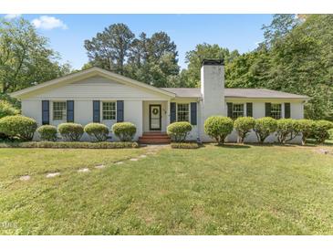 Charming white brick home with black shutters and a well-manicured front lawn and stone walkway at 306 Holland Rd, Fuquay Varina, NC 27526