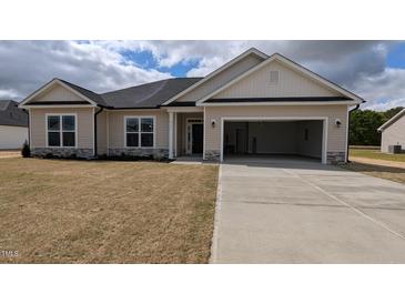 Charming single-story home with a two-car garage, neutral siding, and stone accents under a cloudy, blue sky at 457 Sweet Potato Lane # 13, Nashville, NC 27856