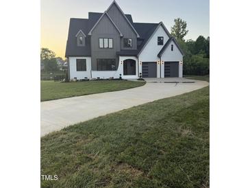 Stunning two-story modern home with gray and white painted brick, a two-car garage, and an inviting curved driveway at 833 Dunleigh Dr, Burlington, NC 27215