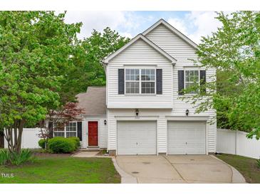 Charming two-story home featuring a bright red door, a two car garage and complemented by mature trees and landscaping at 104 Harvolly Dr, Holly Springs, NC 27540