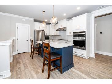 Bright kitchen with a blue island, stainless steel appliances and white cabinets at 10530 Sablewood Dr # 112, Raleigh, NC 27617