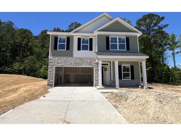 Charming two-story home with stone accents, green siding, and an attached two-car garage at 183 Pecan Valley Way, Four Oaks, NC 27524