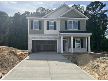 Two-story home featuring an open garage, green siding, a covered porch, and a new concrete driveway at 183 Pecan Valley Way, Four Oaks, NC 27524