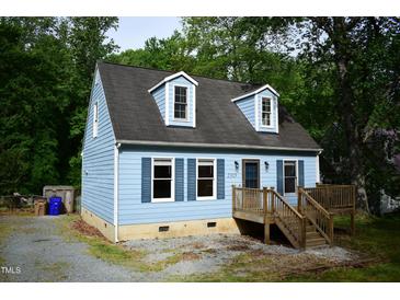 Charming Cape Cod home with light blue siding, a wood deck, and dormer windows nestled in a lush, green setting at 2315 George Anderson Dr, Hillsborough, NC 27278