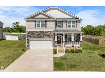 Charming two-story home boasts a stone facade, inviting front porch, and a well-manicured lawn at 2415 Ivy Knoll Dr, Mebane, NC 27302