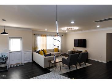 Open living room featuring modern lighting, hardwood floors, and comfortable seating at 428 Parlier Dr, Apex, NC 27523