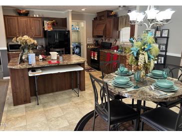 Kitchen and dining area with dark cabinetry, a kitchen island, and a table with decorative place settings at 4855 Mike Ln, Nashville, NC 27856