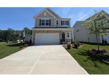 Charming two-story home featuring a two-car garage, stone accents, and a well-manicured front lawn at 521 Morning Light Dr, Angier, NC 27501