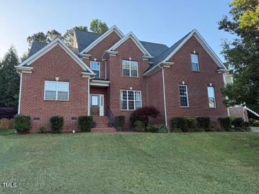 Charming two-story brick home with mature landscaping and a well-manicured front lawn at 1003 Red Sunset Dr, Apex, NC 27502