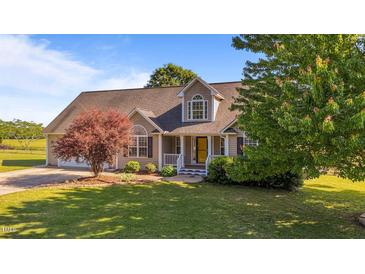 Charming home featuring manicured lawn, mature trees, and a welcoming front porch with a bright yellow door at 106 Contender Dr, Clayton, NC 27520