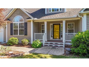 Inviting front porch with white railing, columns, and a vibrant yellow front door at 106 Contender Dr, Clayton, NC 27520