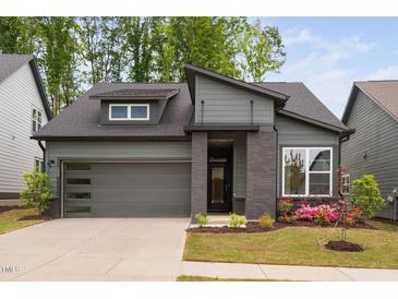 Modern home featuring a dark gray exterior, a two car garage and an inviting front yard at 109 Imagine Way, Pittsboro, NC 27312
