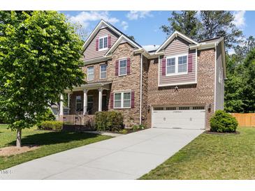 Two-story brick home boasts an attached two-car garage, well-manicured lawn, and covered front porch at 144 Elk Stone Trl, Garner, NC 27529