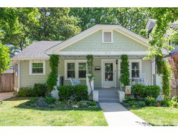 Charming home featuring a landscaped front yard, covered porch with swing, and traditional architectural details at 1714 Carson St, Raleigh, NC 27608