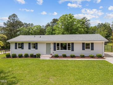 Charming one story home with a well-manicured lawn, lovely landscaping, and a brick pathway leading to the front door at 1734 Stage Rd, Durham, NC 27703