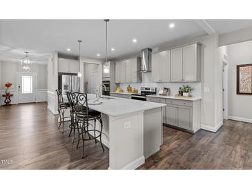 Bright, modern kitchen with gray cabinets, quartz countertops, stainless steel appliances, and a large island with barstool seating at 1816 Sandoval Dr, Durham, NC 27703