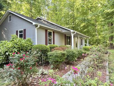 Charming home exterior showcasing a beautifully landscaped front yard with mature flowering plants at 192 Misty Hollow Rd, Timberlake, NC 27583