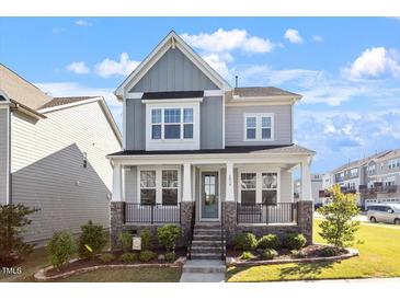 Charming two-story home featuring a welcoming front porch with stone accents and beautifully landscaped yard at 2919 Winter Crop Way, Apex, NC 27502