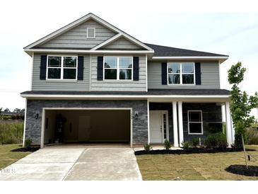 Two-story home with stone accents, black shutters, attached garage, and manicured lawn at 356 Bishop Ln, Sanford, NC 27330