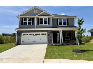 Two-story home featuring gray siding, a stone garage, and a well-manicured lawn at 356 Bishop Ln, Sanford, NC 27330
