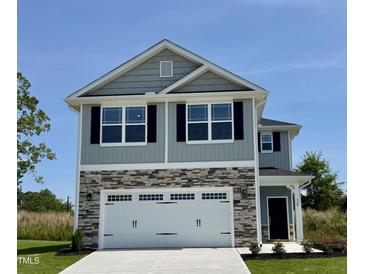 Beautiful two-story home with stone accents, a two-car garage, and manicured landscaping under a bright blue sky at 538 Middleton Ct, Sanford, NC 27330