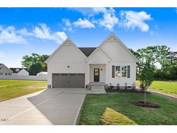Charming white two-story home featuring a gray garage door, well-manicured lawn, and inviting front porch at 72 Glenwood Pl, Kenly, NC 27542