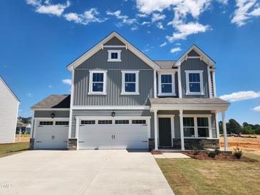 Charming two-story home featuring gray siding, white trim, and a spacious three-car garage and well manicured lawn at 105 S Mule Way # 89, Benson, NC 27504