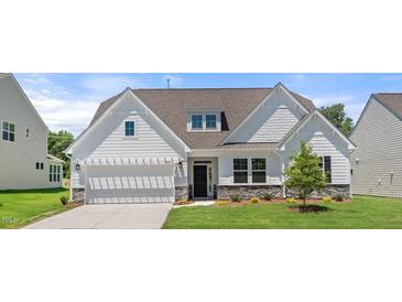 Charming home with a white exterior, well-manicured lawn, a two-car garage and stone accents at 1306 Cricket St, Elon, NC 27244