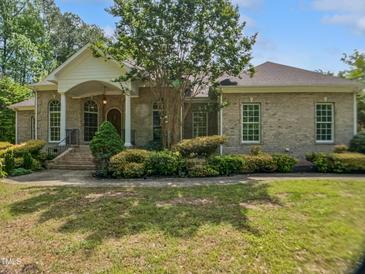 Charming brick home featuring a manicured lawn, elegant columns, and a welcoming front porch at 280 Dreamcatcher Trl, Youngsville, NC 27596