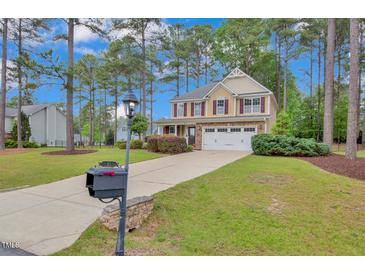 Charming two-story home with a well-manicured lawn and a long driveway leading to an attached two-car garage at 35 Pine Water Way, Spring Lake, NC 28390