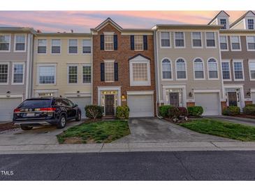 Charming brick townhome with attached garage and manicured front lawn at sunset at 5504 Crabtree Park Ct, Raleigh, NC 27612