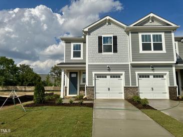 Charming townhome featuring a one-car garage, gray siding, and lovely landscaping on a well-maintained green lawn at 58 Twin Birch Dr, Angier, NC 27501