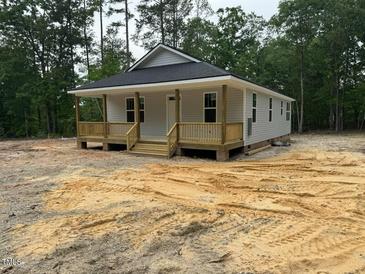 Charming single-story home featuring a welcoming front porch and light gray siding, nestled in a wooded setting at 604 Natchez Trace, Fuquay Varina, NC 27526