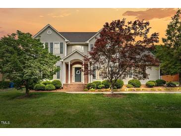 Charming two-story home boasts a manicured lawn and inviting front entrance at sunset at 608 Driftwood Dr, Gibsonville, NC 27249