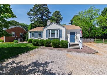 Charming single-story home featuring blue shutters, fresh landscaping, and gravel driveway on a sunny day at 713 E Whitaker Mill Rd, Raleigh, NC 27608