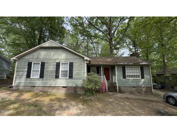 Charming single-story home featuring light green siding, brick foundation, and classic black shutters, framed by mature trees at 7312 Ray Rd, Raleigh, NC 27613