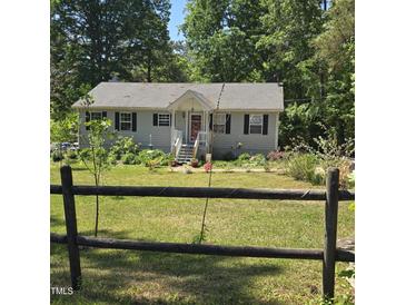 Charming one-story home with gray siding, black shutters and a well-manicured front yard and garden at 106 Palomino Cv, Louisburg, NC 27549
