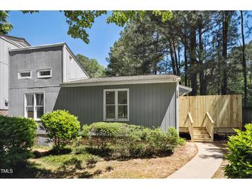 Inviting gray home featuring a cozy front yard with lush green bushes and a charming wooden fence at 112 Carmichael Ct, Cary, NC 27511