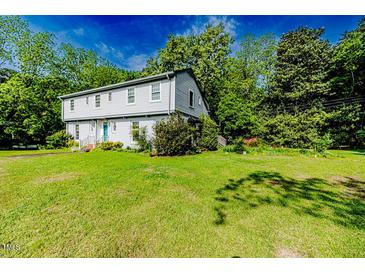 Charming two-story home with light grey siding, surrounded by mature trees and lush green lawn at 1706 Carthage St, Sanford, NC 27330