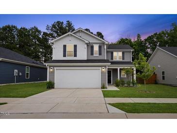 Charming two-story home featuring a two-car garage, a well-manicured lawn, and gray siding under a twilight sky at 230 Purple Aster St St, Youngsville, NC 27596