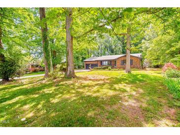 A charming brick home with a well-maintained lawn and mature trees offers a serene and inviting curb appeal at 2509 Elderwood Ln, Burlington, NC 27215