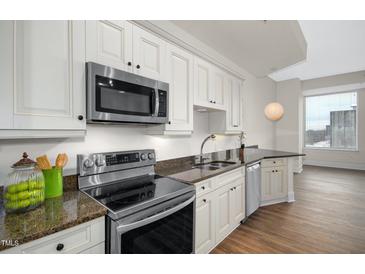 Modern kitchen featuring stainless steel appliances, granite countertops, and white cabinets at 400 W North St # 814, Raleigh, NC 27603