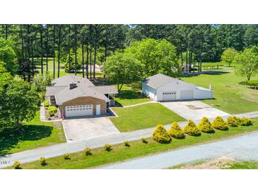 A beautiful brick home features a detached garage, a well-manicured lawn, and mature trees at 4418 Carpenter Pond Rd, Durham, NC 27703