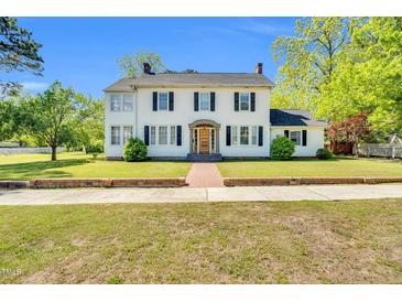Charming two-story white home featuring black shutters and a welcoming front entrance with a brick walkway at 506 S King Ave, Dunn, NC 28334