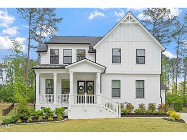 Charming two-story home with a welcoming front porch, black trimmed windows, and beautifully landscaped yard at 7616 Hasentree Way, Wake Forest, NC 27587