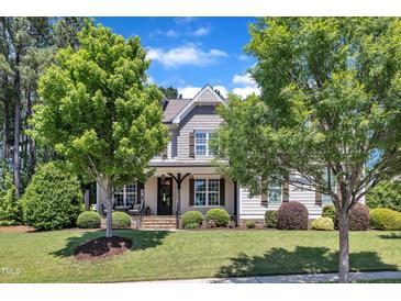 Charming home with a beautiful yard, featuring mature trees, landscaping, and a covered front porch at 1012 Wandering Way, Rolesville, NC 27571