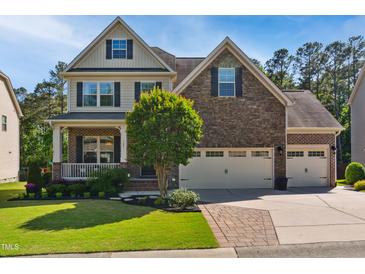 Charming two-story home with a stone and brick facade, a well-manicured lawn, and a two car garage at 106 Mesquite Dr, Durham, NC 27703