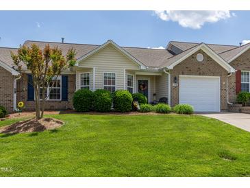 Charming brick home featuring a well-manicured lawn, mature landscaping, and a welcoming front entrance at 1410 Osborne Dr, Burlington, NC 27215